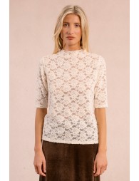 Woman wearing a white lace top against a pink background