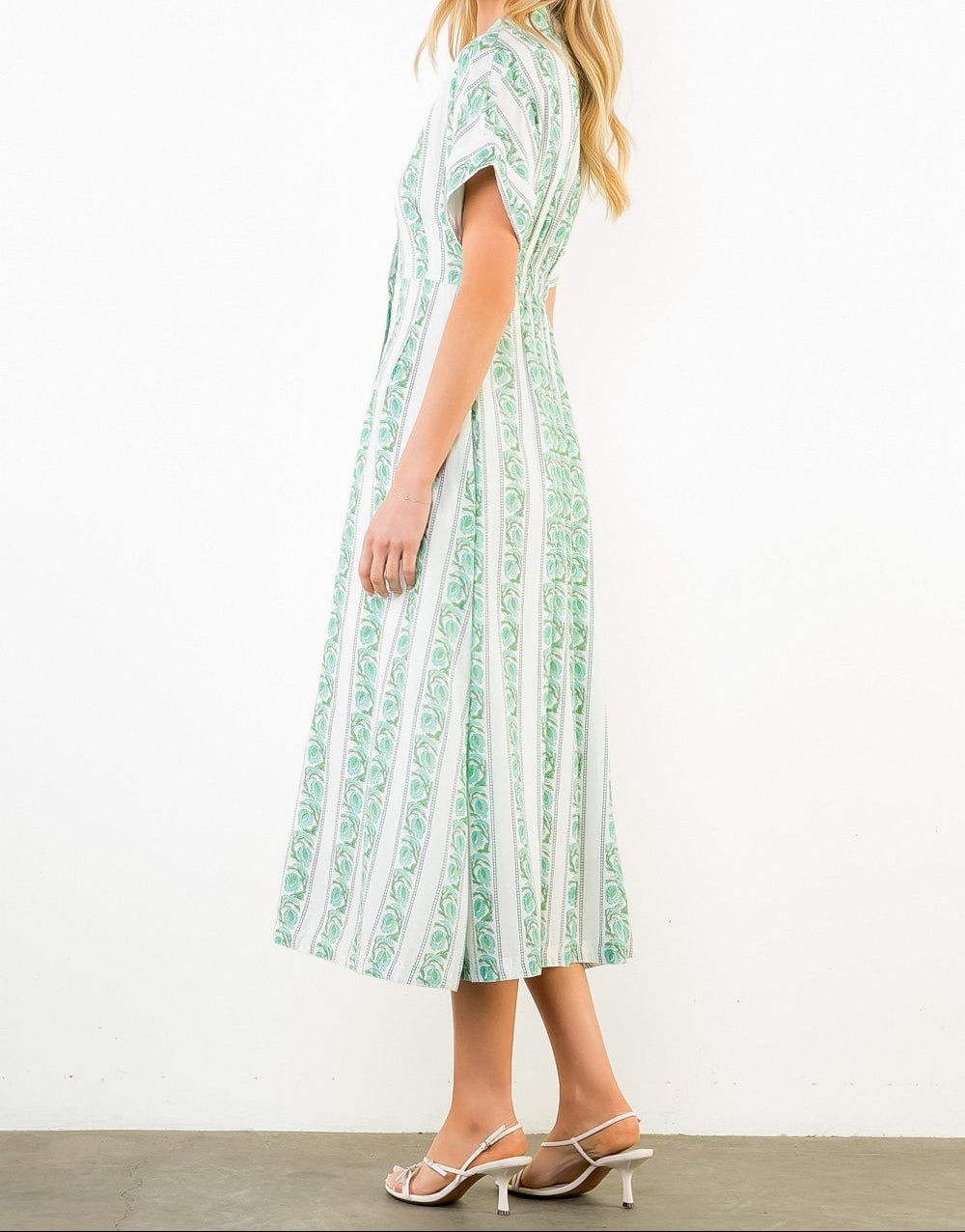 Woman wearing a green and white patterned dress on a white background