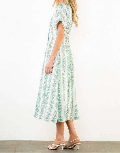 Woman wearing a green and white patterned dress on a white background