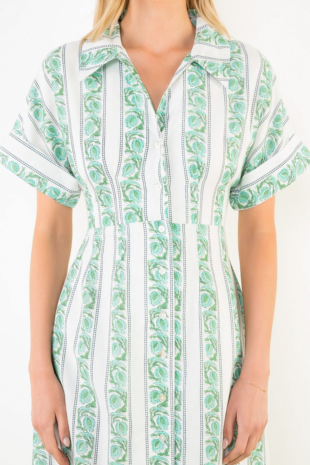 Green and white patterned dress worn by a person on a plain background
