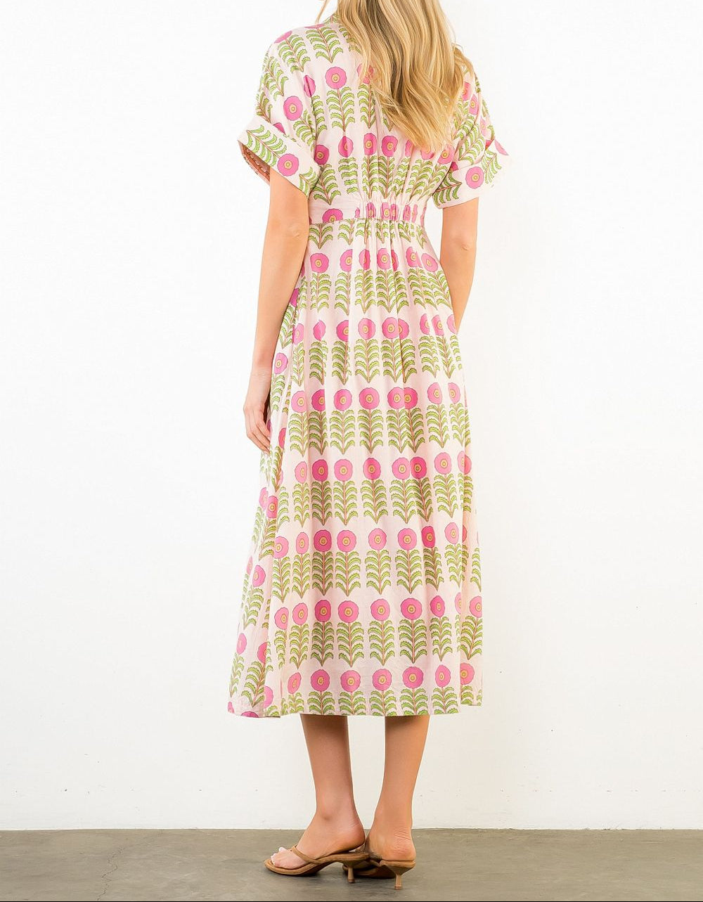 Woman wearing a patterned dress with pink and green design on a white background