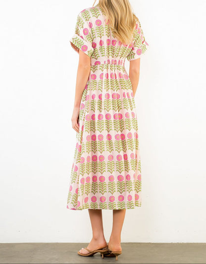 Woman wearing a patterned dress with pink and green design on a white background