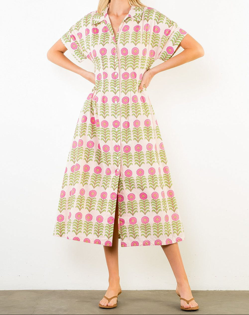 Woman wearing a patterned dress with pink and green design against a white background