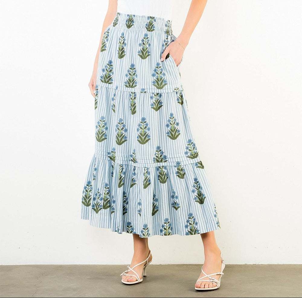 Woman wearing a white top and blue floral skirt on a white background