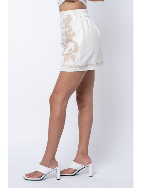 White skirt with floral embroidery worn by a person on a white background