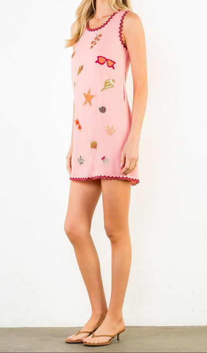 Woman wearing a pink dress with decorative elements on a white background